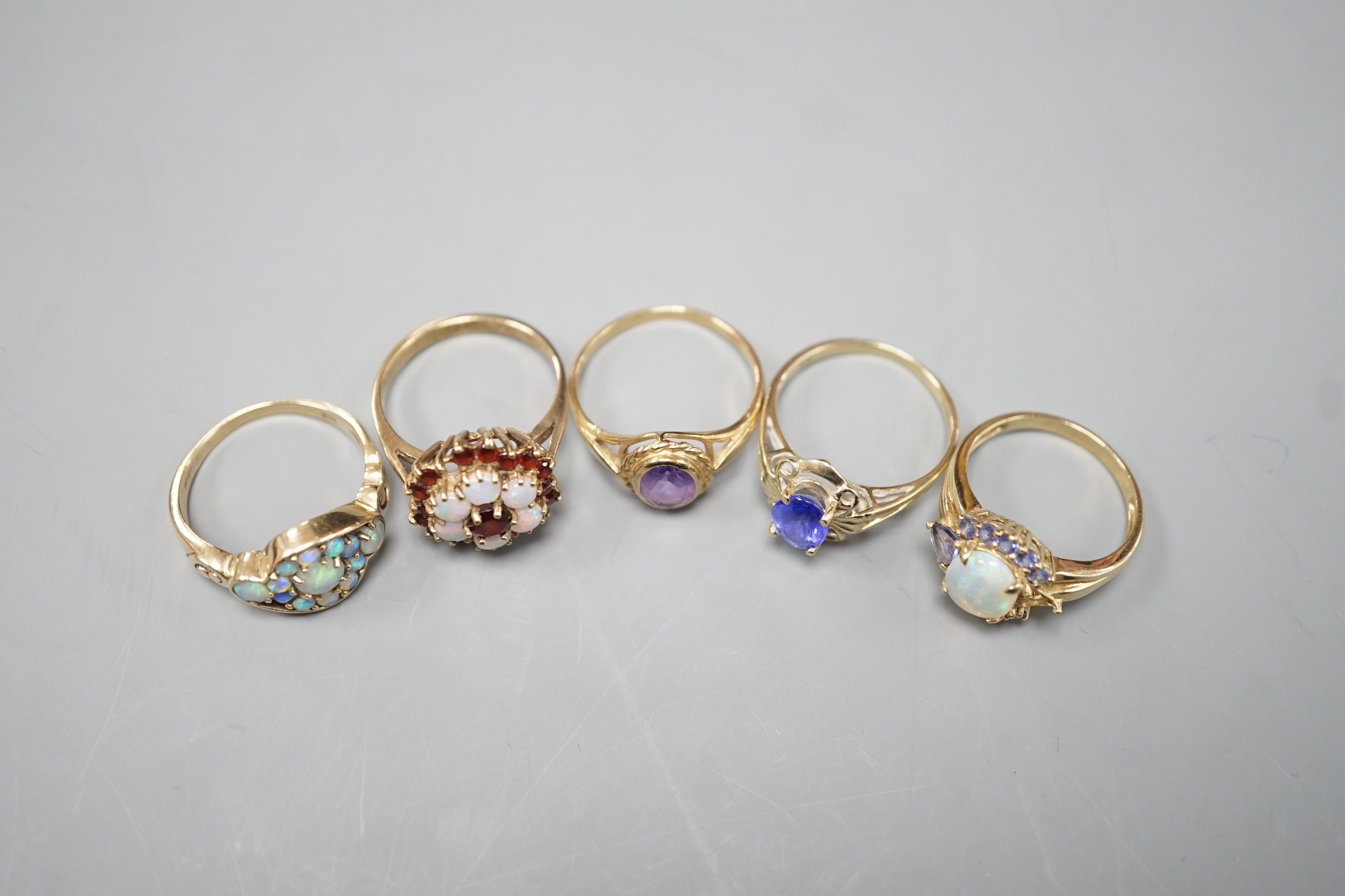 Five assorted modern 9ct gold and gem set dress rings, including, white opal cluster, garnet and white opal cluster and amethyst